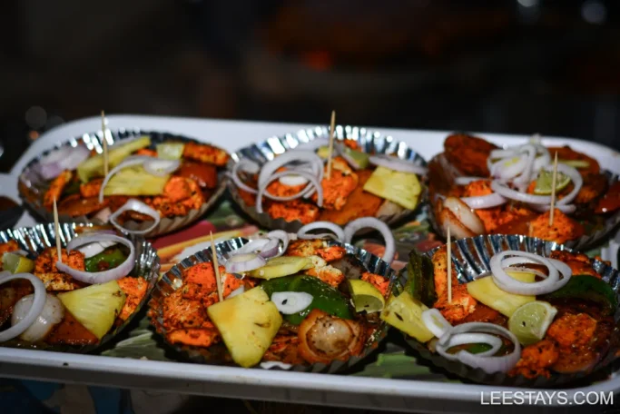 A variety of colorful, grilled appetizers served on small plates at Diamond Resort near Pawna Lake, featuring paneer, bell peppers, pineapple, and onion slices, garnished thoughtfully for presentation.