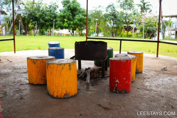 Colorful wooden stools around a fire pit in a garden setting, possibly part of lakeview cottages at Pawna.