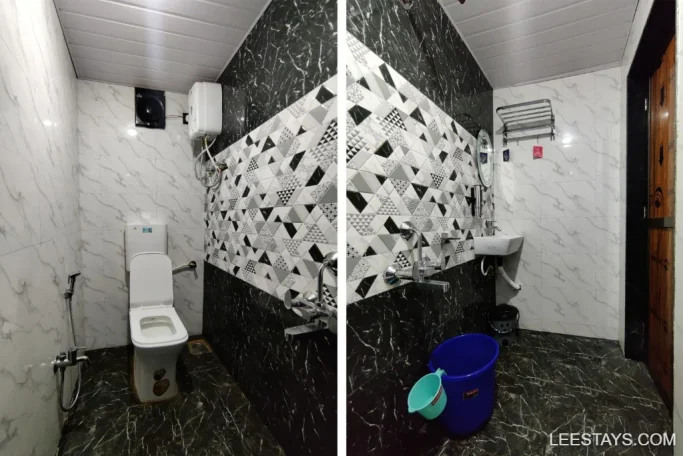 Modern bathroom with geometric black and white design, located at a lakeside retreat in Pawna, featuring a toilet, sink, and water heater.