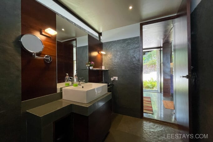 Bathroom interior at a resort near Pawna Lake, featuring a modern sink, mirror, and window view of greenery.