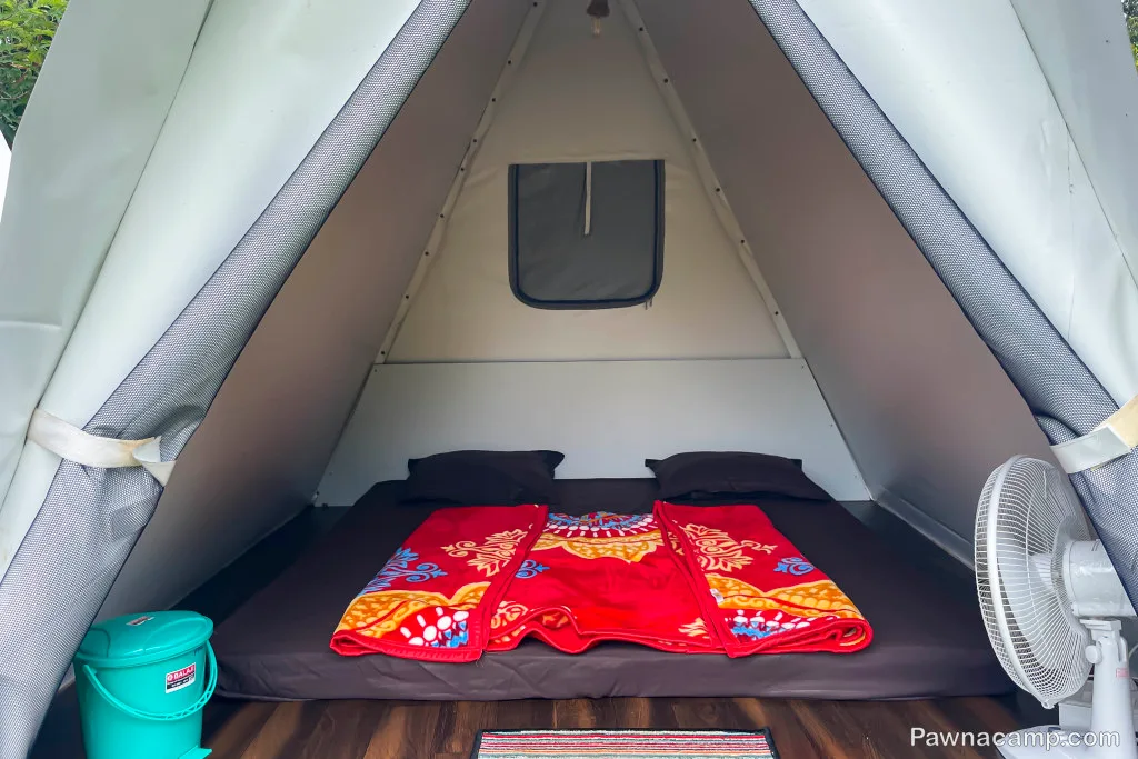 Cozy tent setup with colorful bedding and fan, ideal for a stay at Pawna Lake with rustic charm and comfort.