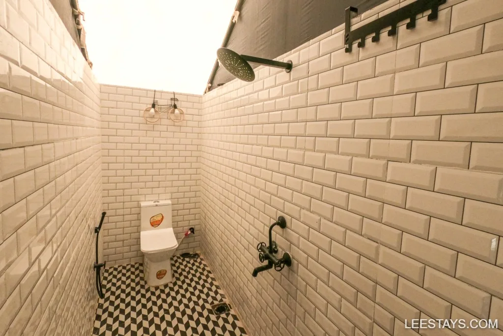 Modern bathroom with geometric tiles and shower, typical of glamping sites near Pawna Lake, featuring white subway tile walls and a stylish overhead light.