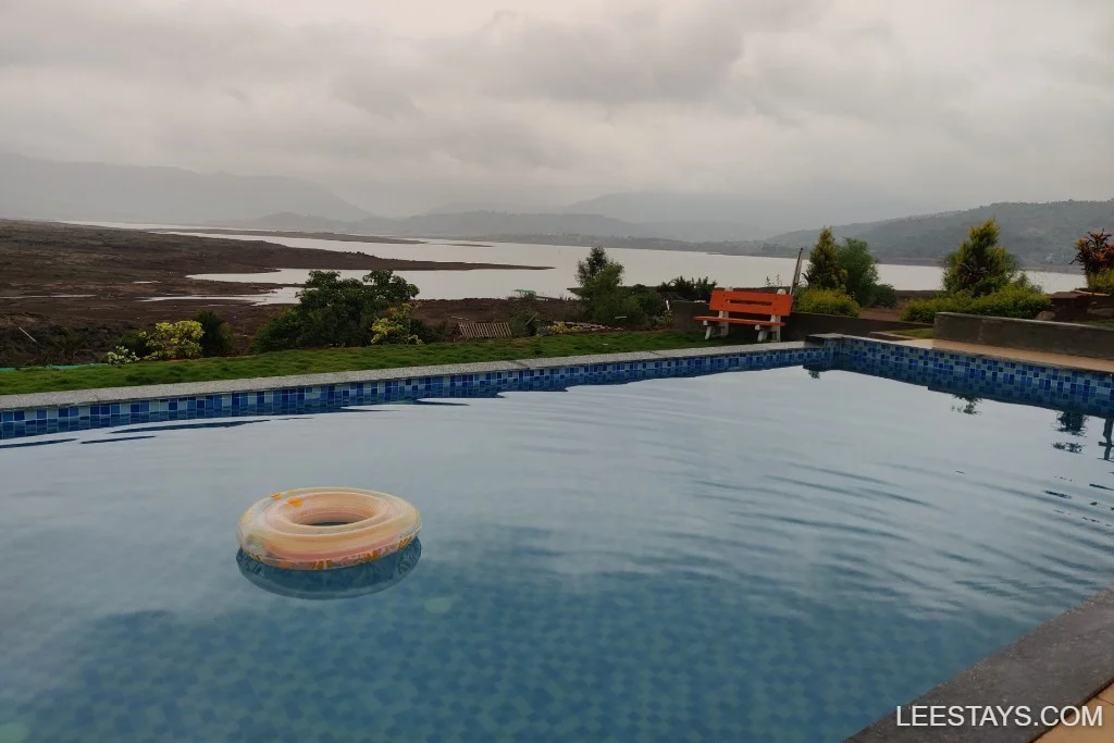 Lakeside retreat near Pawna with a tranquil pool overlooking scenic hills and a serene lake, ideal for relaxation.