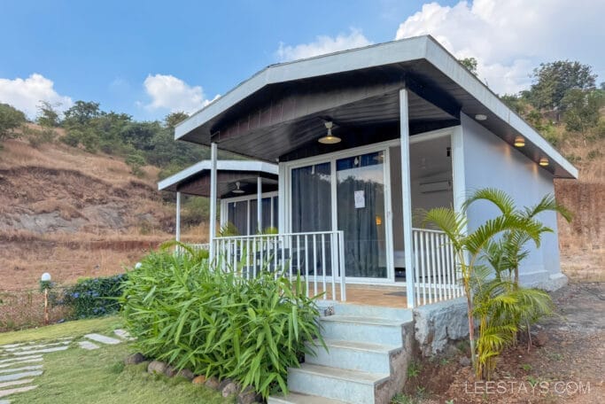 Premium cottages by Pawna Lake with modern design, surrounded by lush greenery and scenic hillside views.